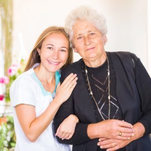 Young caregiver hugging a smiling older woman