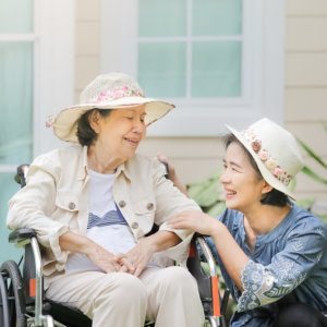 Caregiver and older woman laughing together outdoors