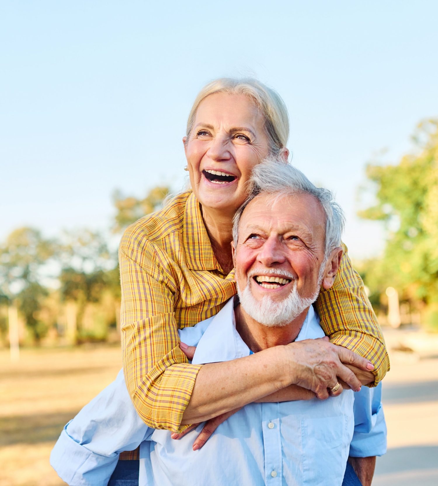 Older couple laughing together outdoors on a sunny day