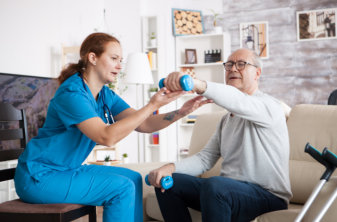 physiotherapist assisting senior man in exercising